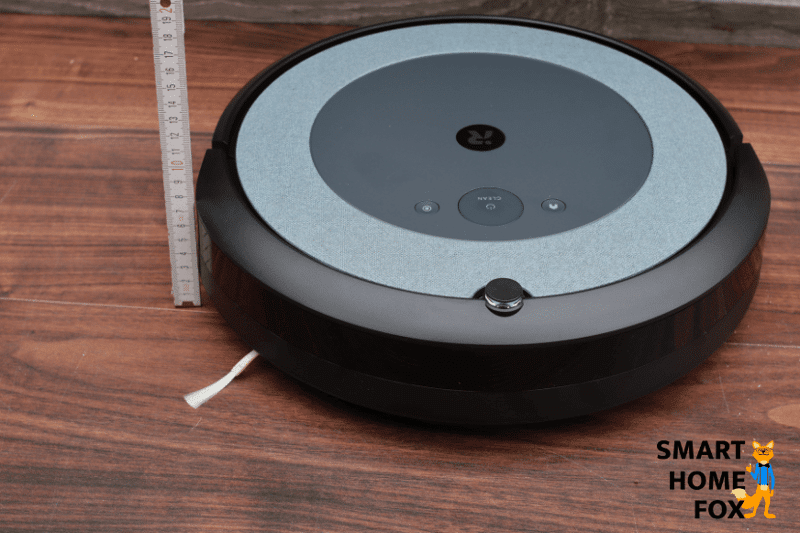 Measuring the height of an iRobot Roomba vacuum robot with a ruler.